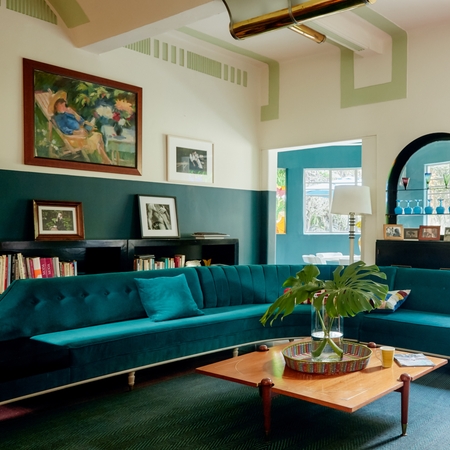 一间明亮通风的客厅，放着蓝绿色沙发。